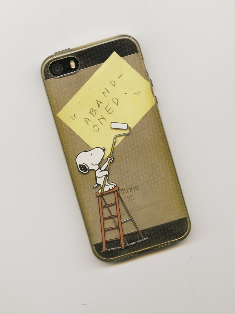 flatbed scan of iphone with snoopy case and a postit